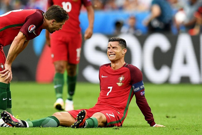 PARIS, FRANCE - JULY 10: Cristiano Ronaldo of Portugal lies injured as teammate Adrien Silva of Portugal (L) checks on him during the UEFA EURO 2016 Final match between Portugal and France at Stade de France on July 10, 2016 in Paris, France. (Photo by Laurence Griffiths/Getty Images)
